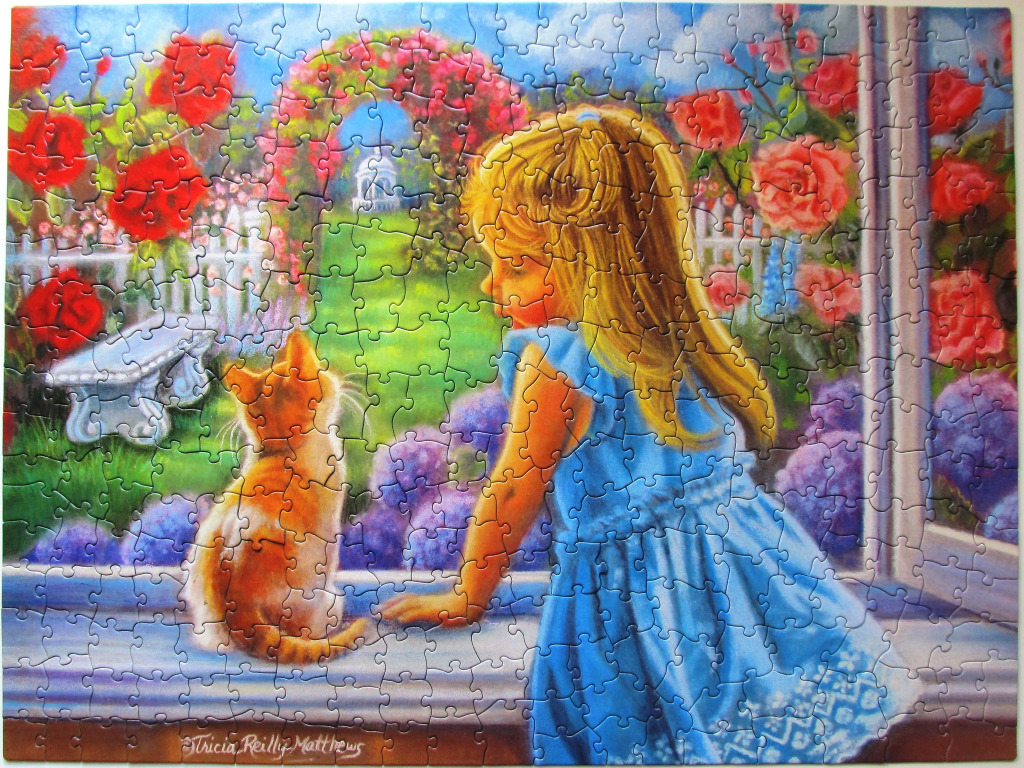 A young blonde girl in a blue dress and a ginger kitten look out a window at a vibrant rose garden.