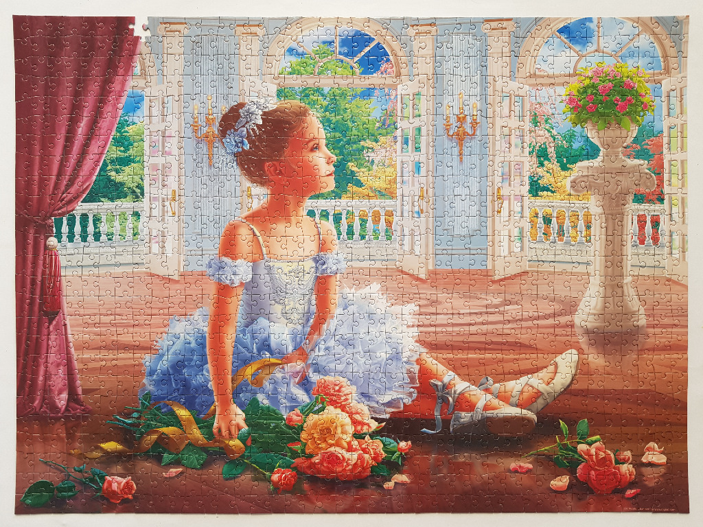A young girl in a blue ballet dress sits on a wooden floor in a grand room with arched windows and flowers.
