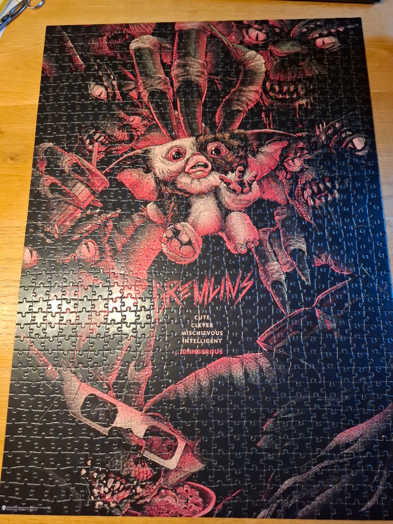 Stylized illustration featuring a central Gremlin surrounded by dark, monstrous figures in a red and black color palette.