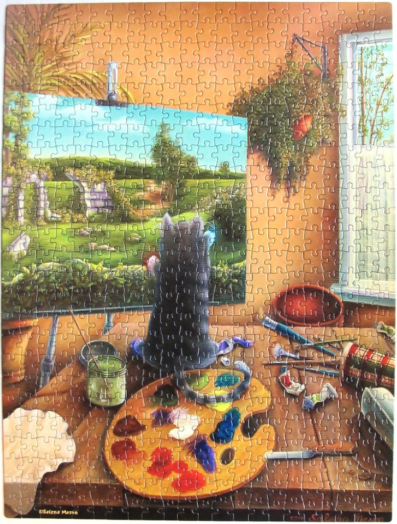 A grey cat sits on a wooden desk looking at a landscape painting on an easel in a sunlit room.