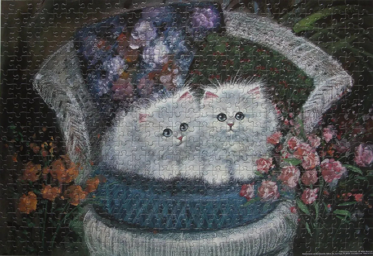 Two fluffy white kittens sitting together in a wicker basket surrounded by flowers