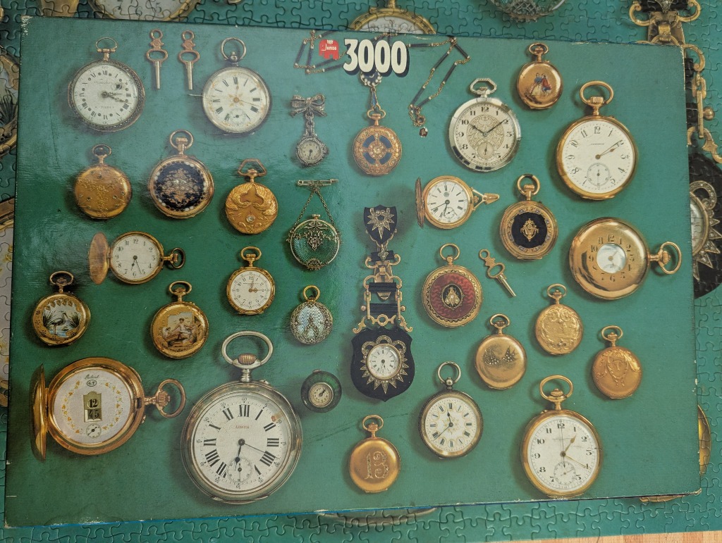 Collection of various vintage pocket watches and watch keys arranged on a teal green background.