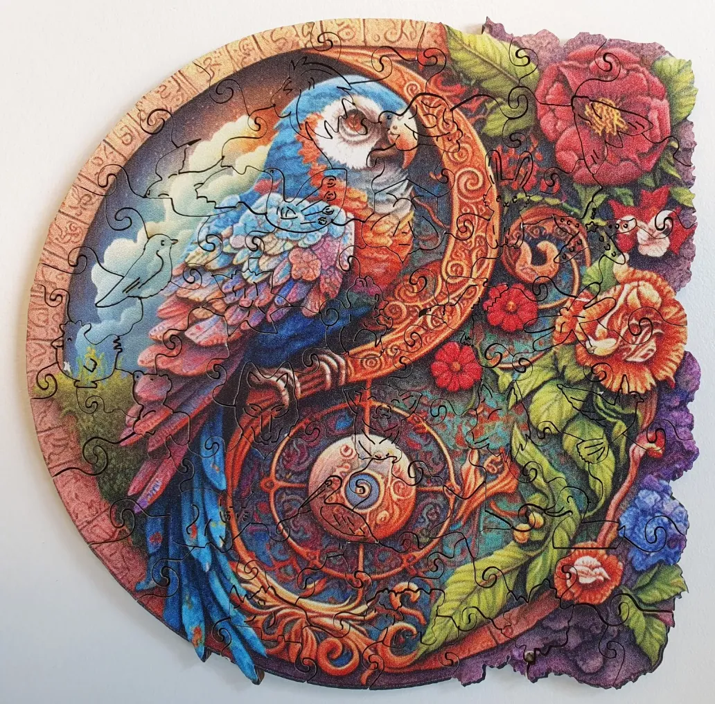 A circular fantasy illustration featuring a vibrant blue parrot intertwined with a yin-yang floral and celestial design.