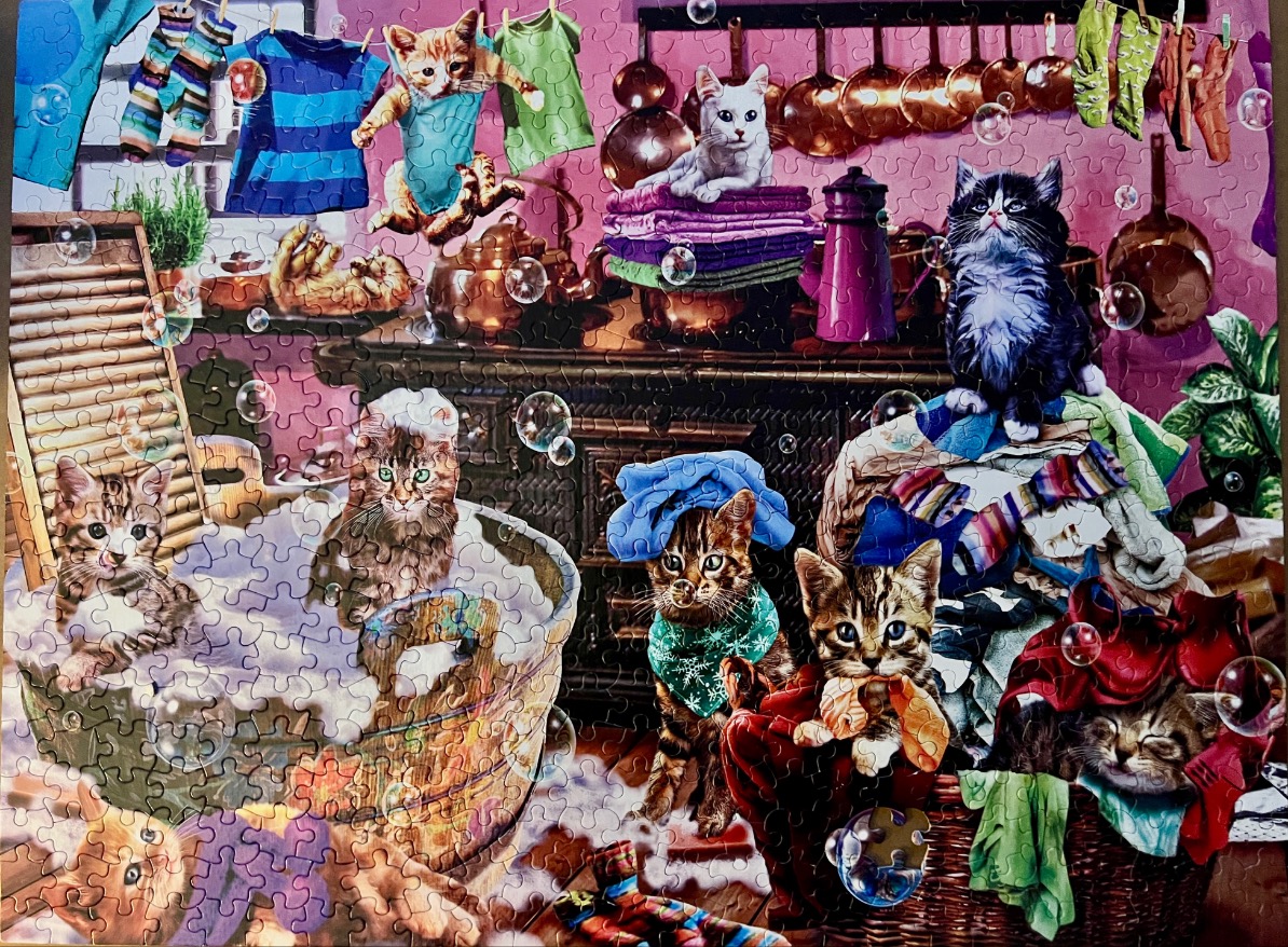 A whimsical illustration of many kittens helping with laundry in a kitchen setting.