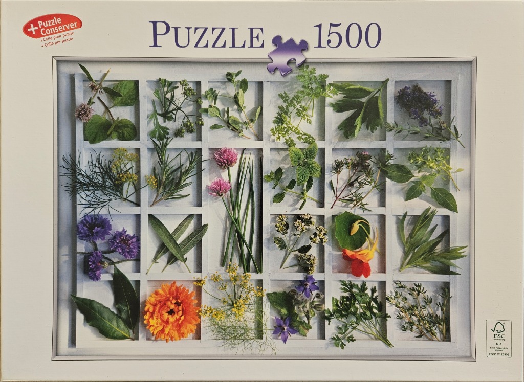 A grid of fresh herbs and edible flowers arranged in a white wooden shadowbox frame.