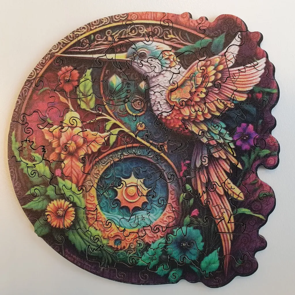 A whimsical circular illustration featuring a hummingbird, a sun motif, and various small animal silhouettes.