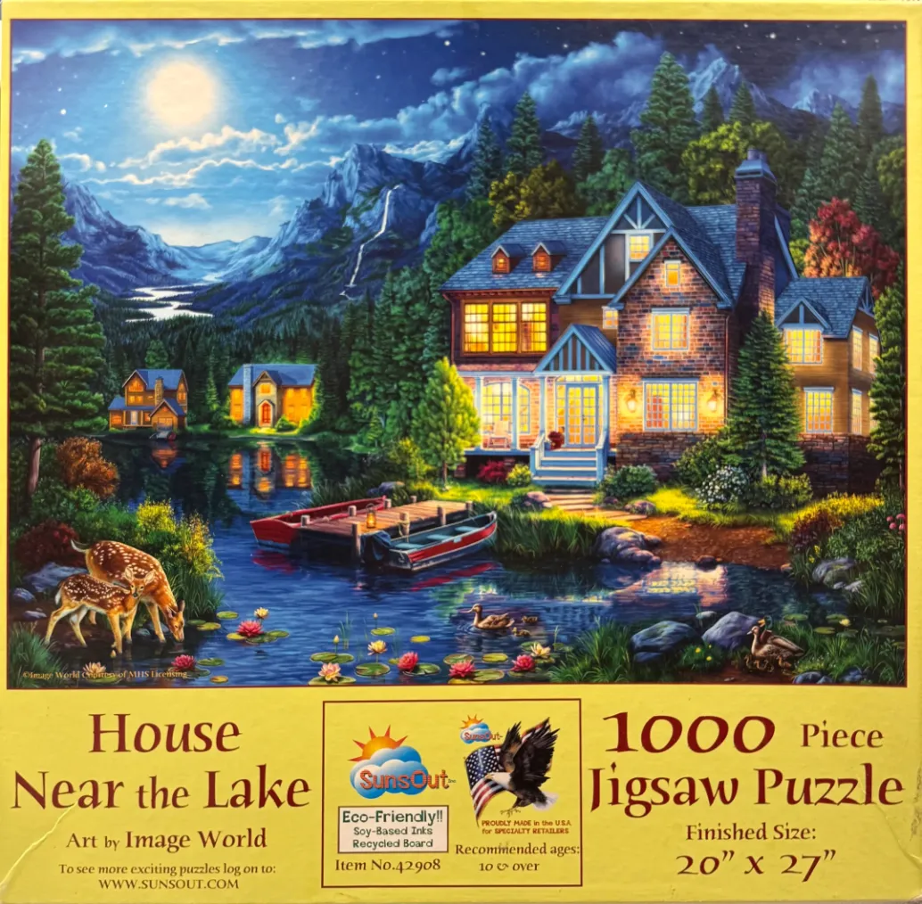 A peaceful lakeside scene at night featuring a warm-lit house, mountains, and deer by the water.