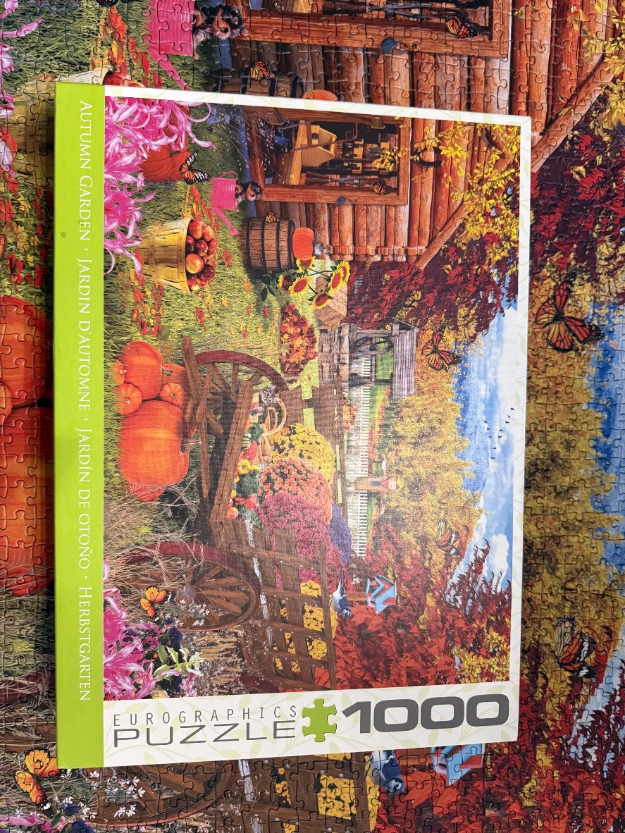 An autumnal garden scene featuring a rustic wooden cart filled with pumpkins, surrounded by flowers and butterflies.