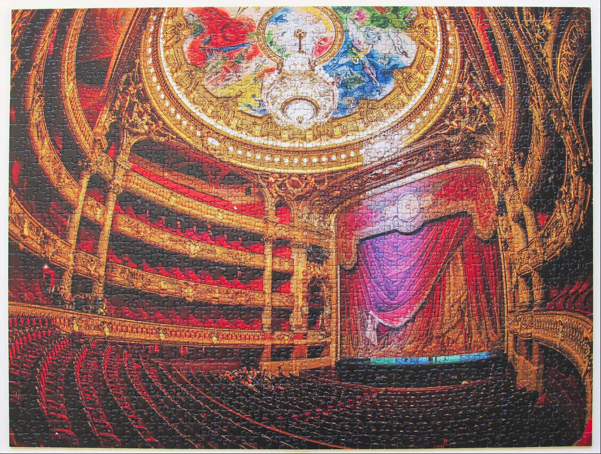 Interior view of the ornate Paris Opera House with red velvet seating, gold gilding, and a painted ceiling fresco.