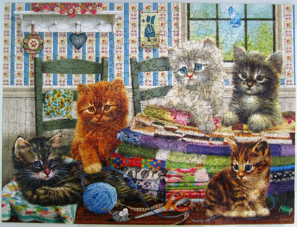 Four kittens playing with yarn and fabric in a country-style room