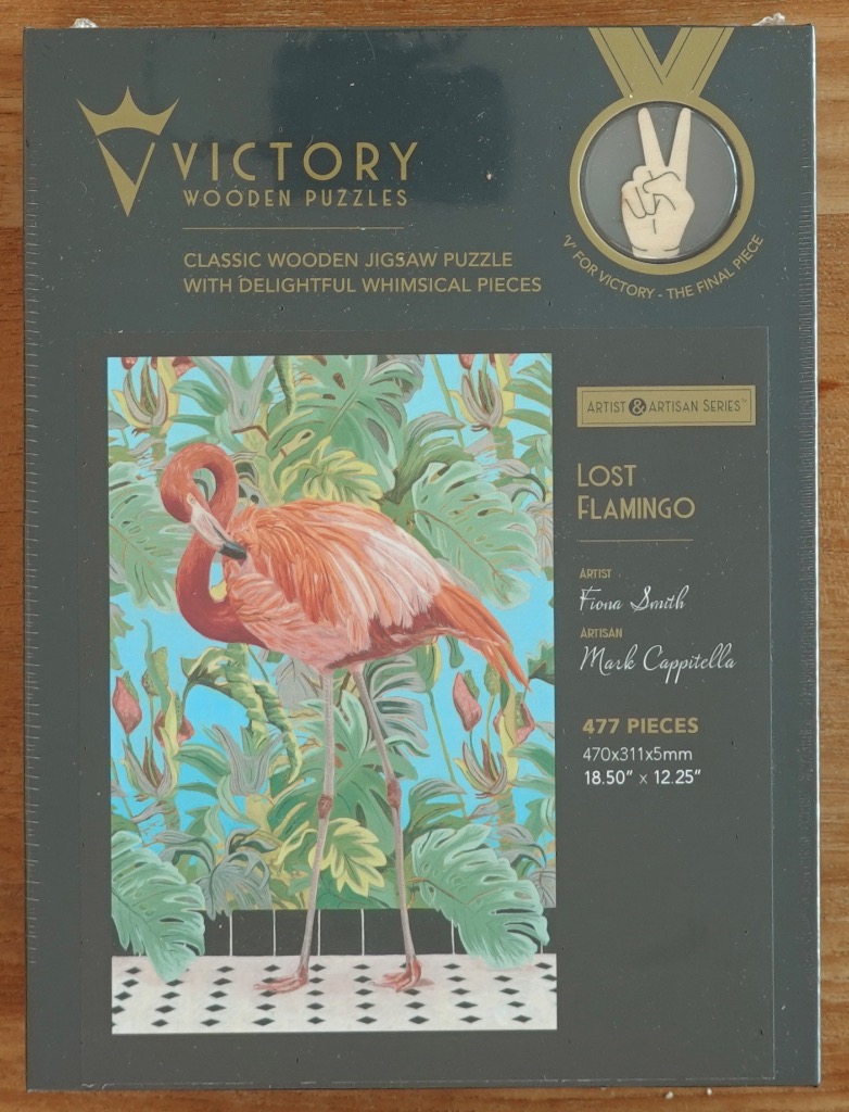A flamingo preening its feathers in front of a lush tropical plant backdrop.