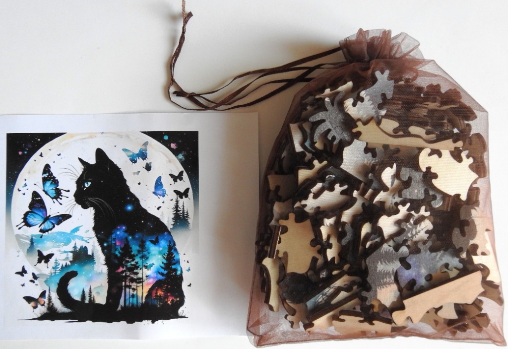 A black cat silhouette image with a galaxy theme next to a sheer brown drawstring bag filled with wooden cutouts.