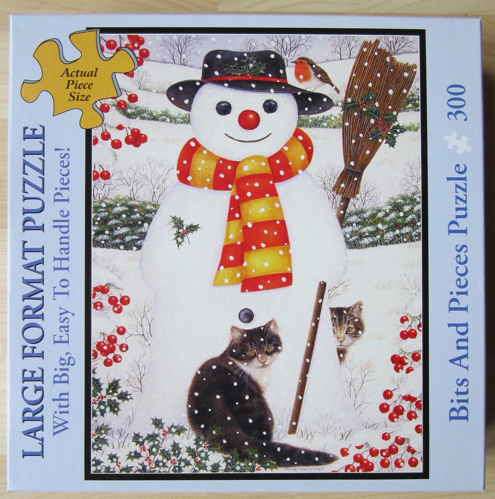 A festive snowman wearing a hat and striped scarf, with two cats and a robin in a snowy landscape.