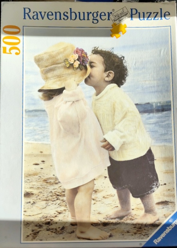 A young girl in a sun hat and a young boy standing together on a beach.