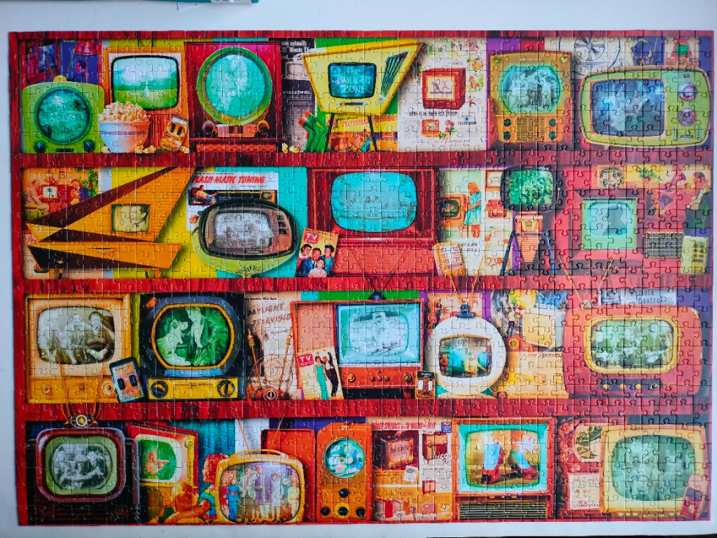 A collage of vintage mid-century television sets arranged on shelves against a wood-panelled background.
