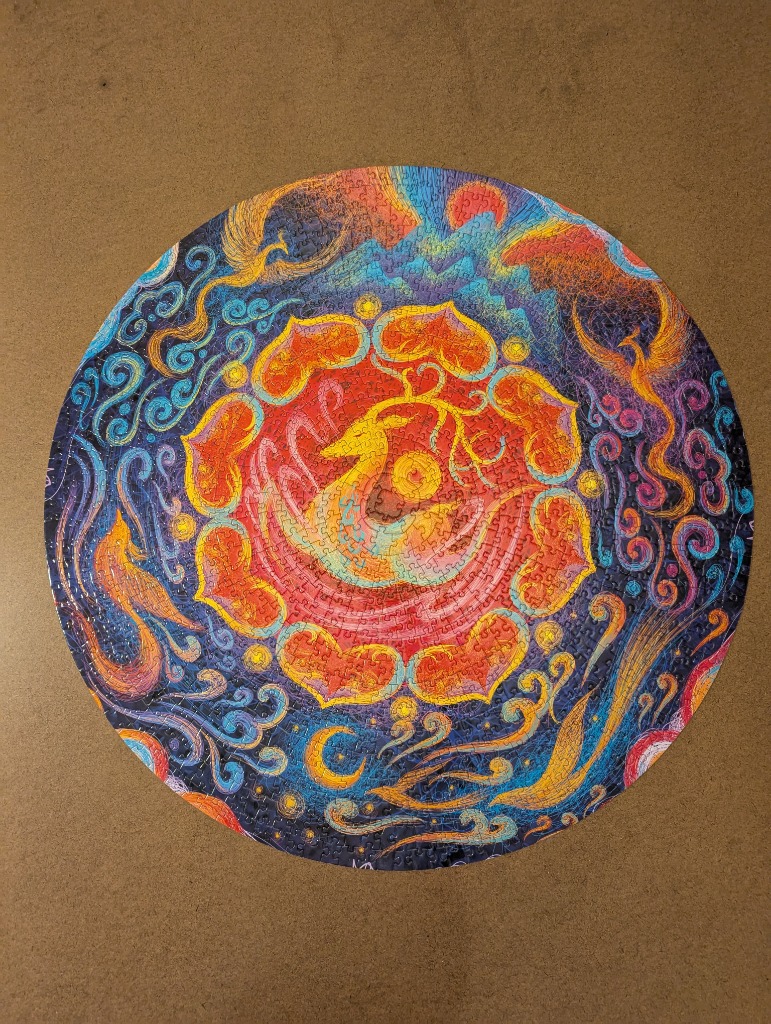 Circular illustration of a phoenix amidst flowing clouds and stylized suns