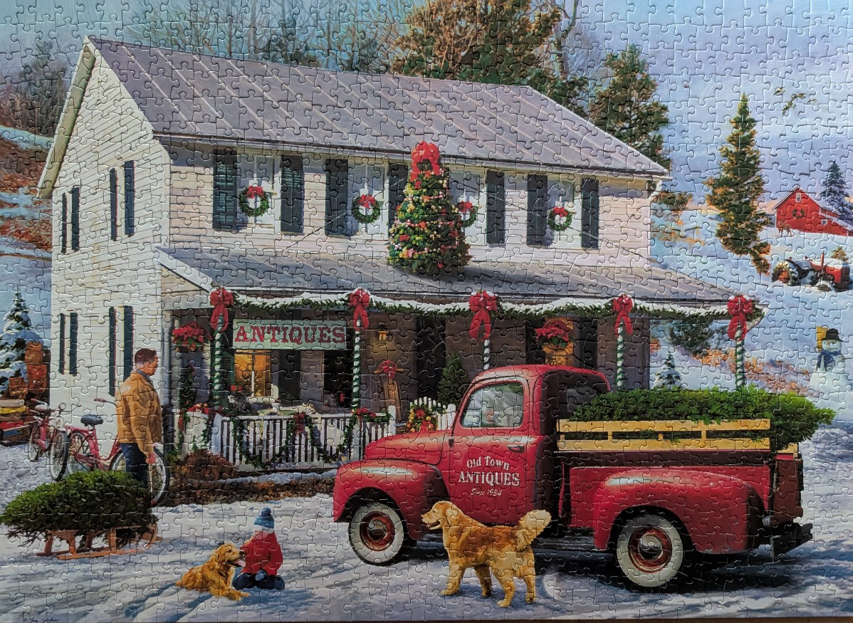 A festive, snow-covered antique shop scene with a red vintage truck, golden retrievers, and a child in winter clothing.