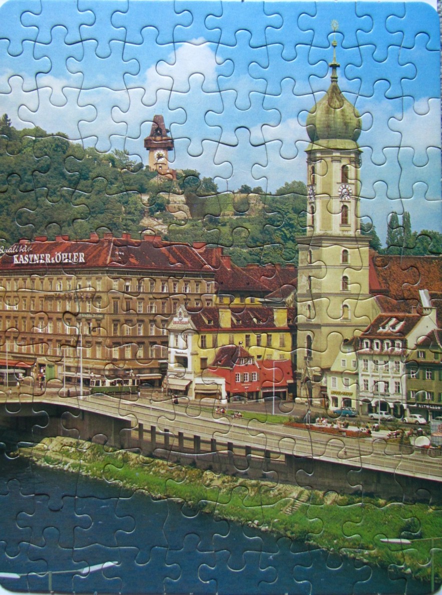 Scenic view of Graz, Austria, featuring the Mur river and the prominent church tower of the Mariahilferkirche.