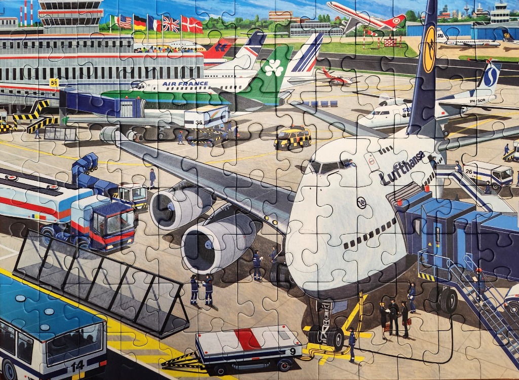 Busy airport tarmac scene featuring a large Lufthansa jet parked at a gate with ground crew and support vehicles.