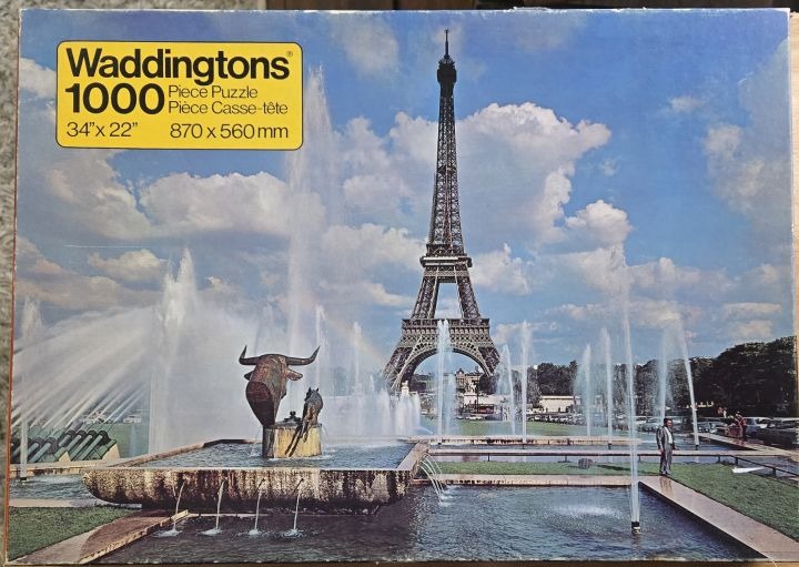 The Eiffel Tower rises behind a large stone fountain featuring a sculpture of a bull in a park-like setting.