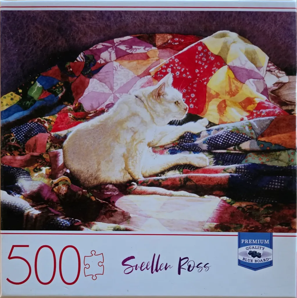 A white cat resting on a colorful patchwork quilt.