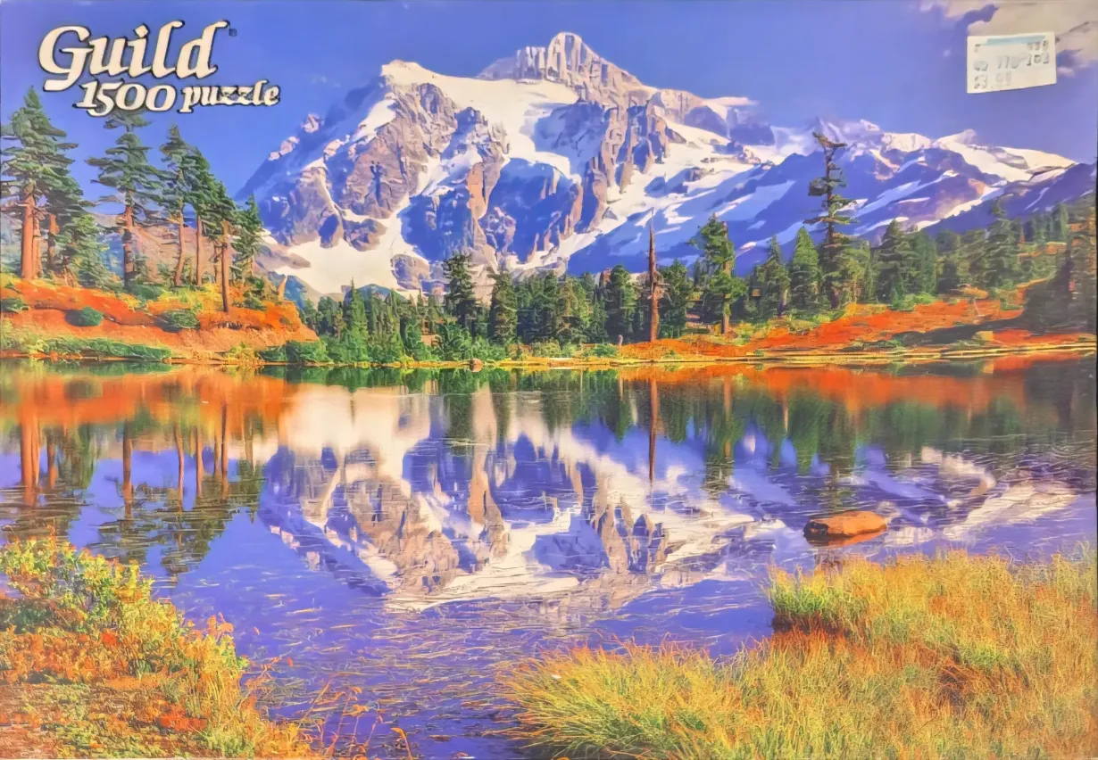 A peaceful landscape featuring a snow-capped mountain reflected in a serene lake surrounded by autumn-toned forests.