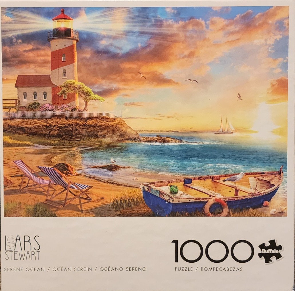 A lighthouse glowing at sunset overlooking a beach with a blue rowboat and two striped lounge chairs.