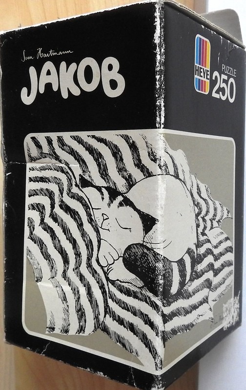 A black and white ink drawing of a cat curled up asleep on a patterned blanket.