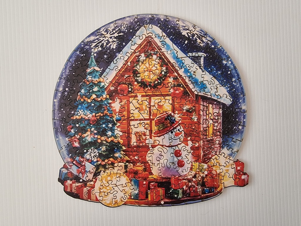 A snow globe scene featuring a cabin, a Christmas tree, and a snowman surrounded by gifts.