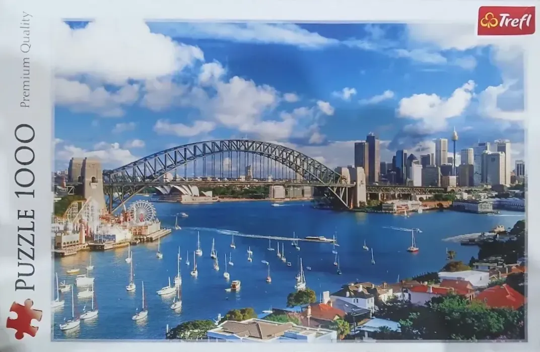 Panoramic view of Sydney Harbour with the Harbour Bridge, Opera House, and skyscrapers under a blue sky
