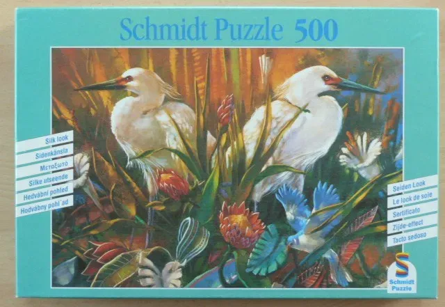 Two white egrets standing amongst vibrant tropical flowers and foliage.
