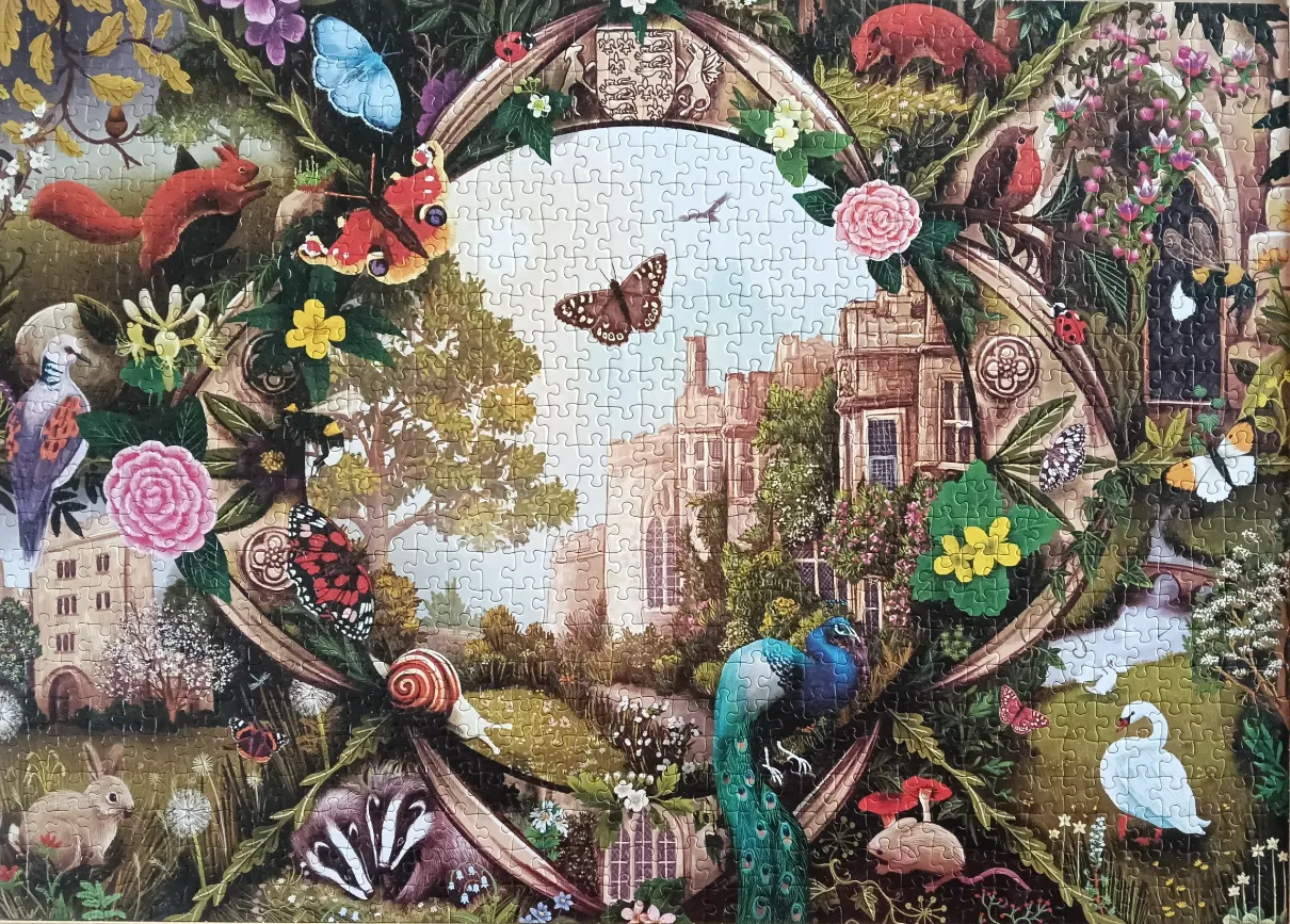 An ornate oval frame decorated with flowers and wildlife, centered on a country estate scene.