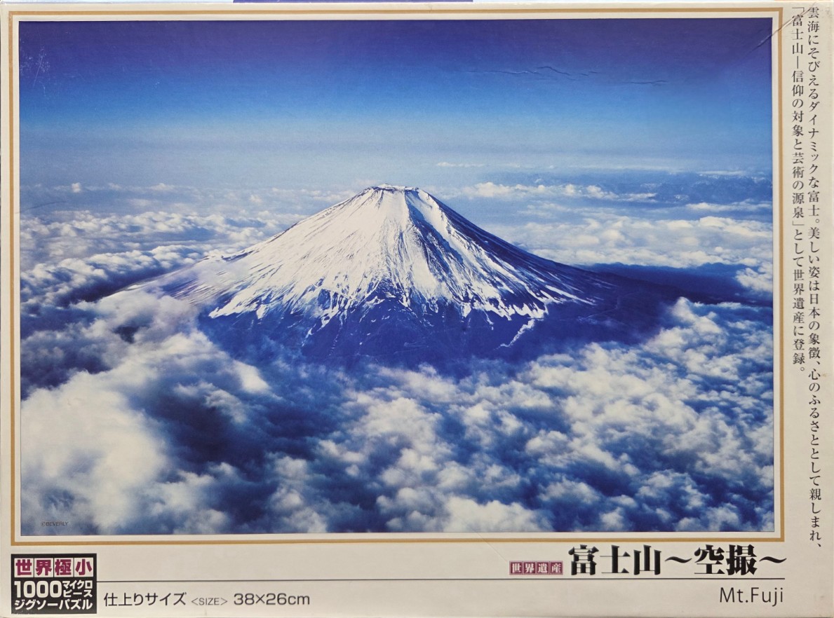 Aerial view of Mount Fuji rising above a thick layer of clouds against a deep blue sky.