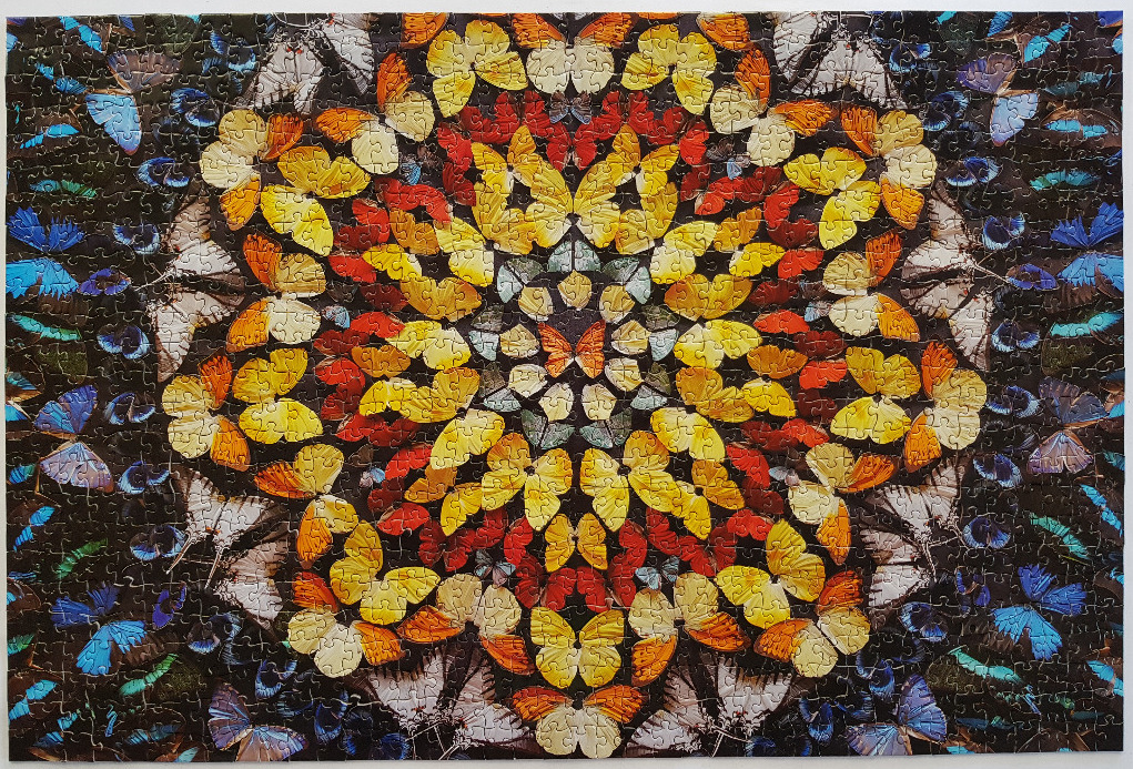 A vibrant mandala pattern composed of numerous butterflies in shades of yellow, orange, blue, and black.