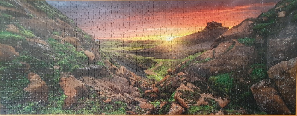 A scenic panoramic view of a lush green mountain valley at sunset.