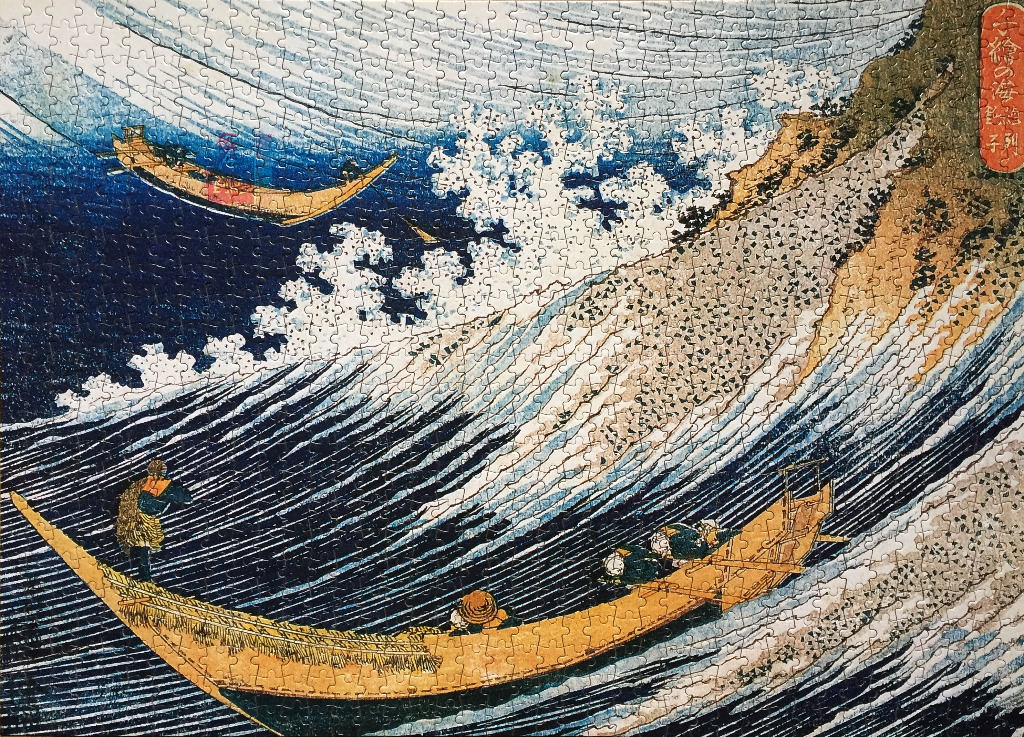 A classic Japanese woodblock print showing two traditional wooden boats navigating turbulent, frothy ocean waves.