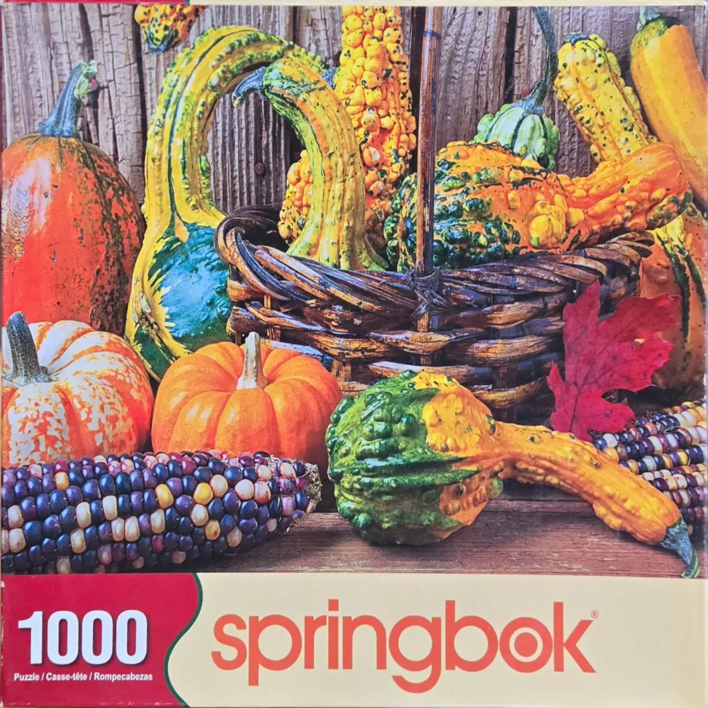 An assortment of autumn harvest items including pumpkins, decorative gourds, and Indian corn in a rustic wicker basket.