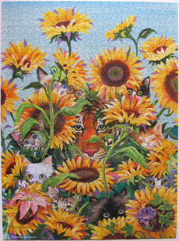 A whimsical illustration of a tiger face and many kittens hiding among vibrant sunflowers against a blue sky.