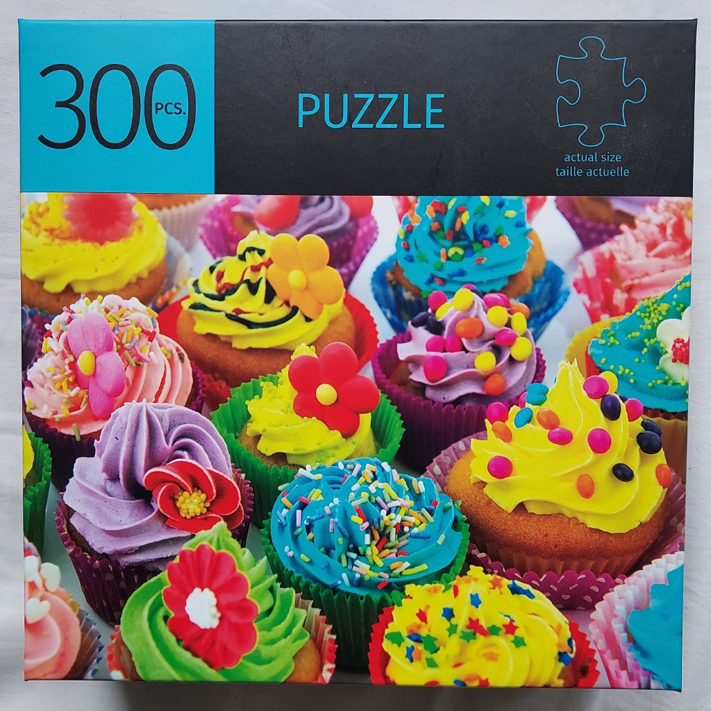 An assortment of vibrantly colored cupcakes topped with bright frosting, sprinkles, and flower-shaped candy decorations.