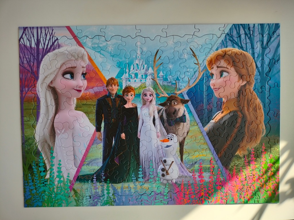 A digital illustration featuring Elsa, Anna, Kristoff, Sven, and Olaf from Frozen 2 against a magical forest background.