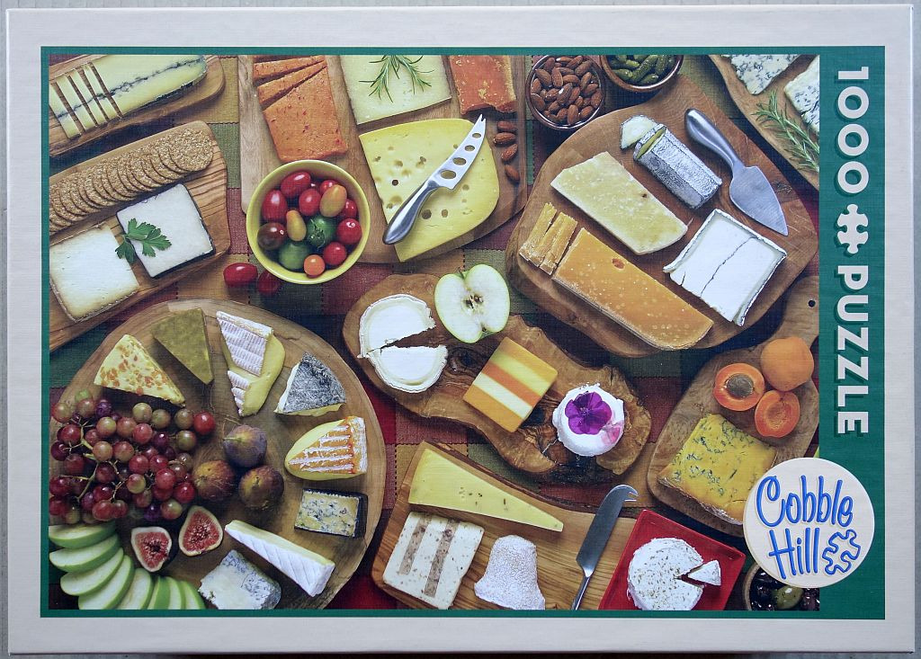 An overhead view of various cheeses, fruits, and crackers arranged on wooden serving boards.