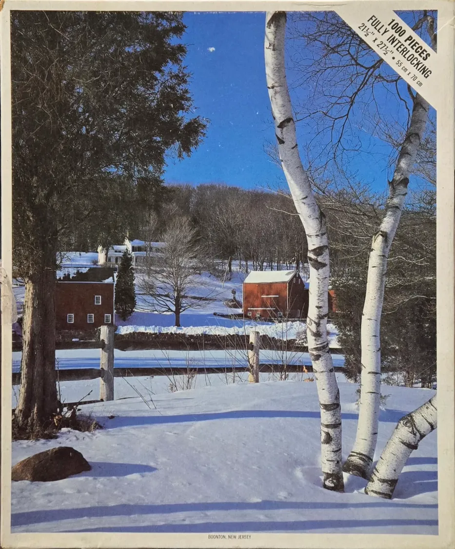 A winter landscape in Boonton, New Jersey featuring red barns and birch trees against a bright blue sky.