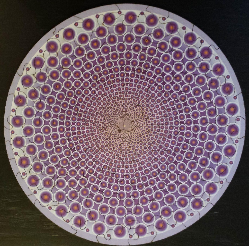 A circular geometric pattern featuring concentric rings of purple and orange orbs spiraling toward a central point.