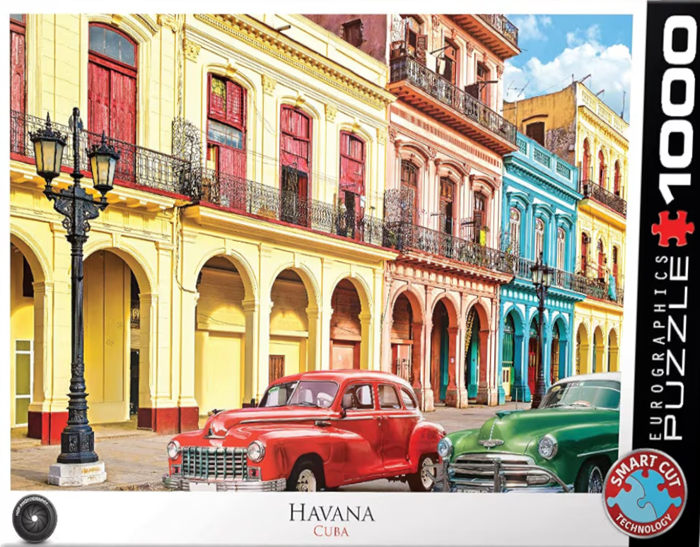 A street scene in Havana, Cuba, featuring vintage red and green cars parked in front of colorful colonial-style buildings.