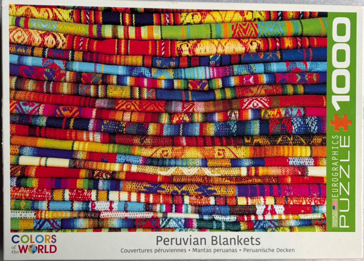 A close-up photograph of a stack of vibrantly colored, patterned Peruvian blankets.