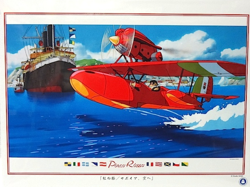 A bright red seaplane flying low over blue water near a large ship in a classic anime style.