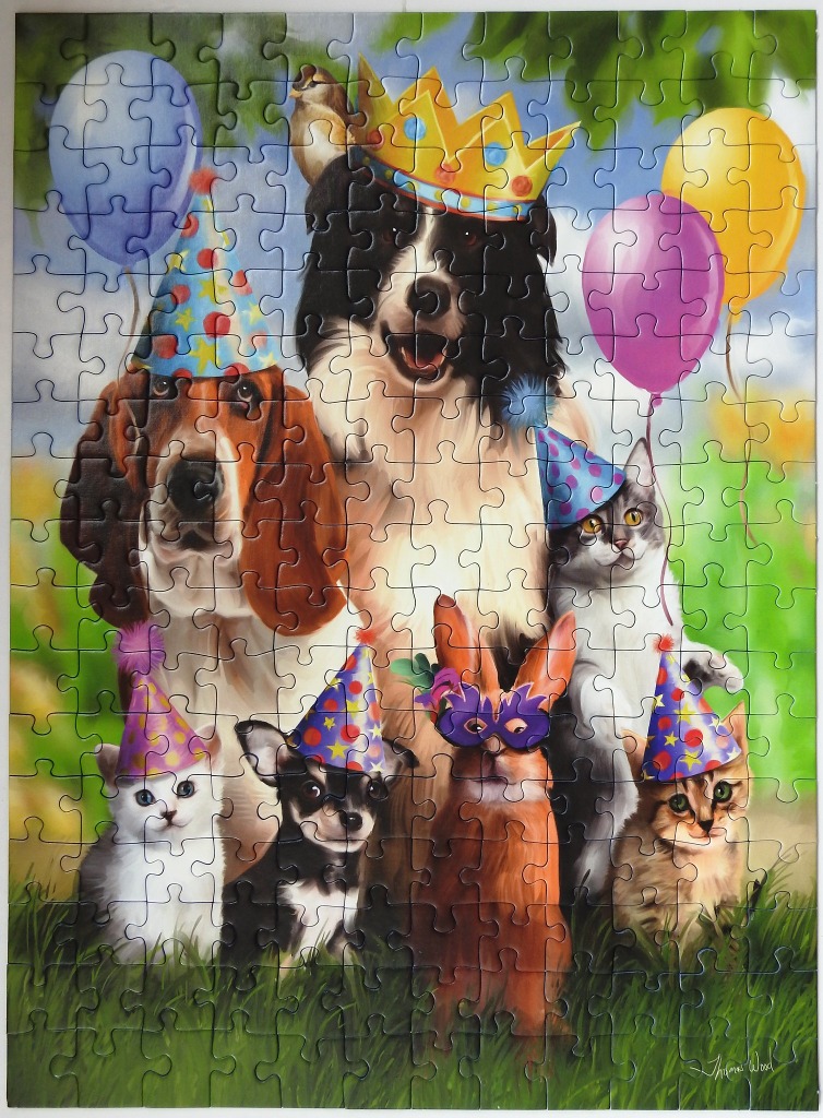 A group of dogs, cats, and a rabbit wearing party hats and costumes in a sunny outdoor setting.