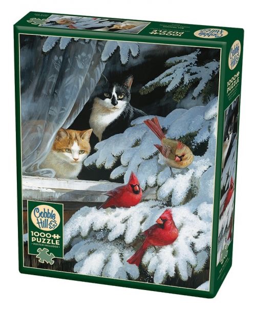 A black and white cat and an orange and white cat watch three cardinals perched on a snowy pine branch outside a window.