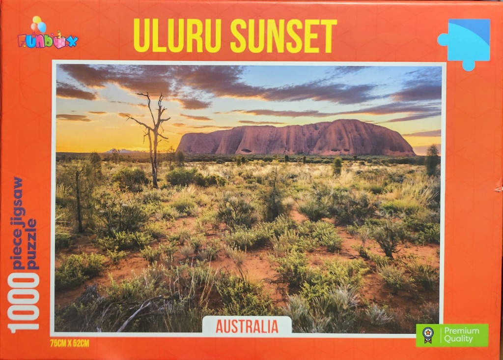 A scenic photograph of Uluru at sunset surrounded by Australian desert flora under a golden sky.
