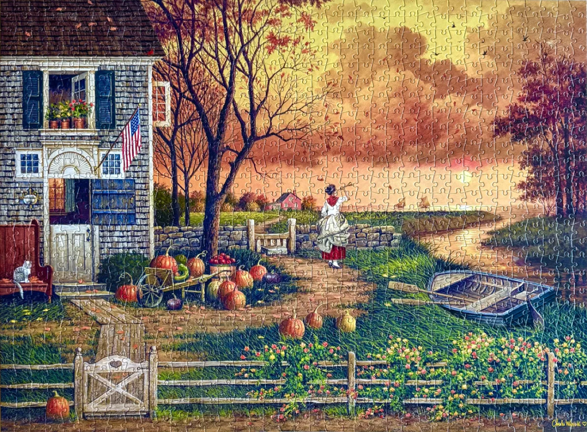 A nostalgic autumn scene featuring a colonial house with pumpkins by the water at sunset.